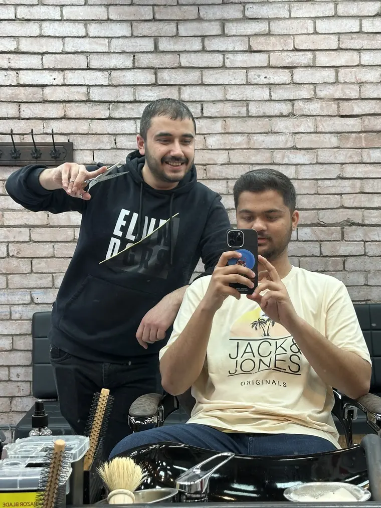 Barber and customer sharing a laugh at the mirror inside Galaxy Barber